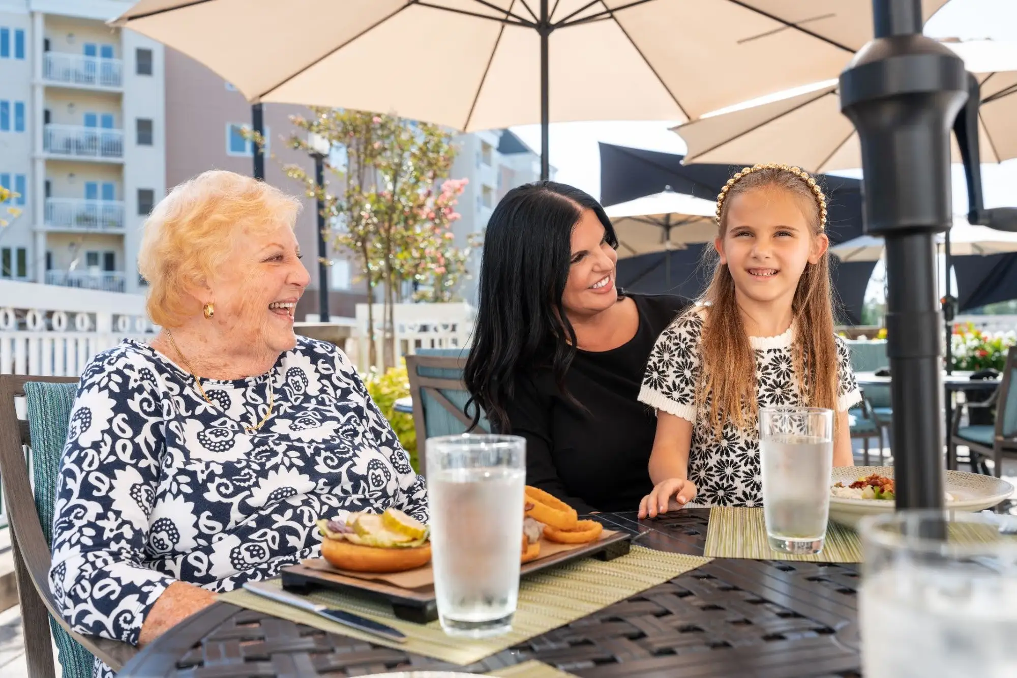 A senior woman with adult daughter and grand daughter enjoying the outside senior living dining venue, The Ridge Pub at Blakehurst in Towson, MD.
