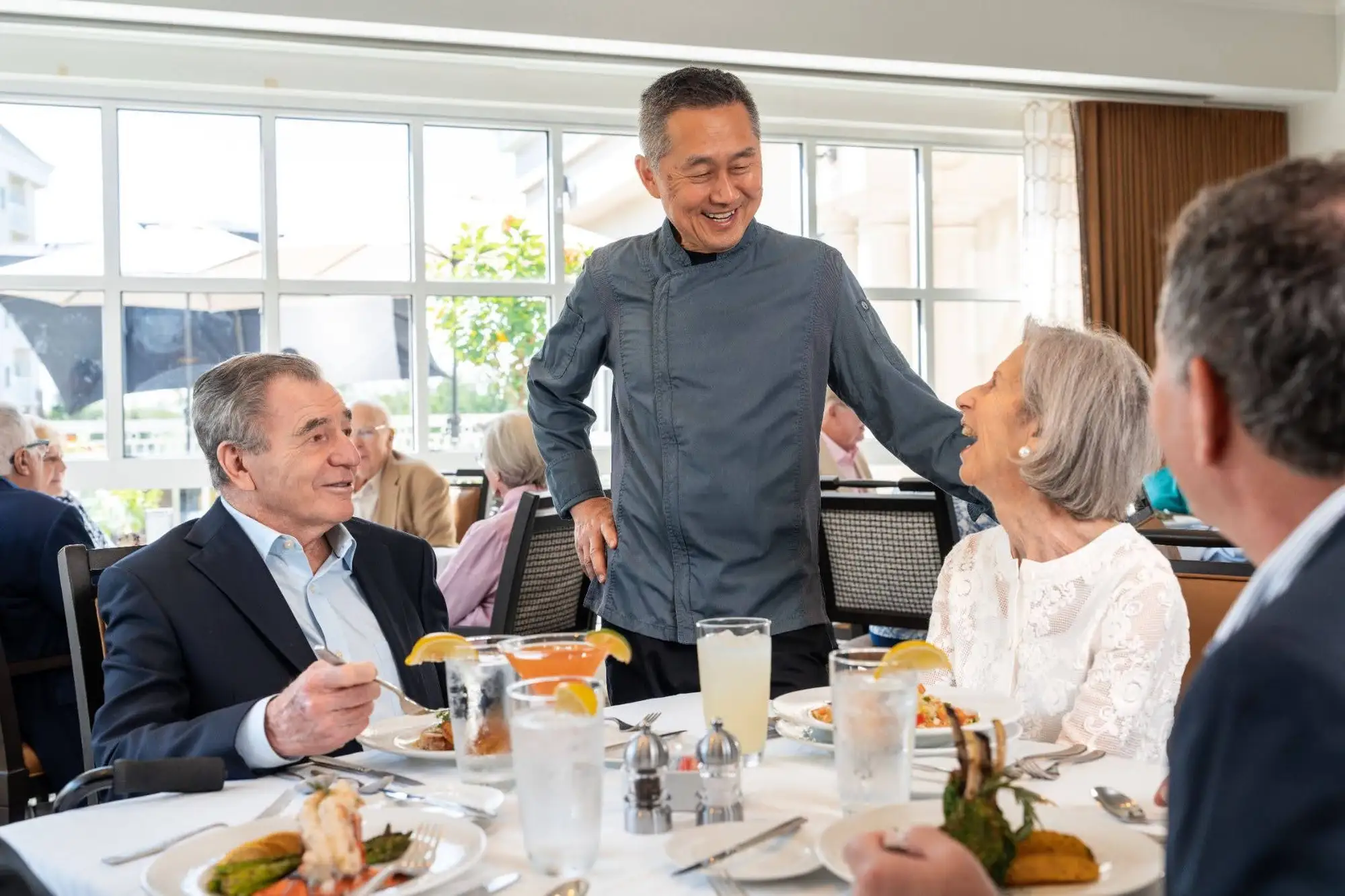 A waiter of The Chesapeake at Blakehurst in Towson, MD, taking an order for a happy senior couple.