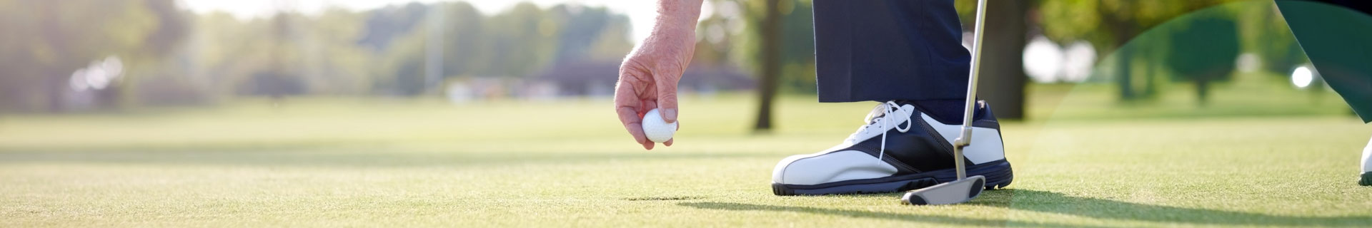 man places golf ball on the green to putt