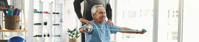 senior man exercises with help of a personal trainer