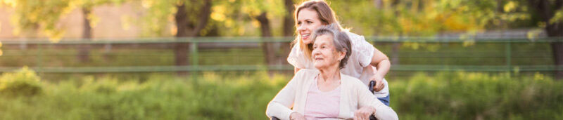 senior health care worker pushes resident in wheelchair