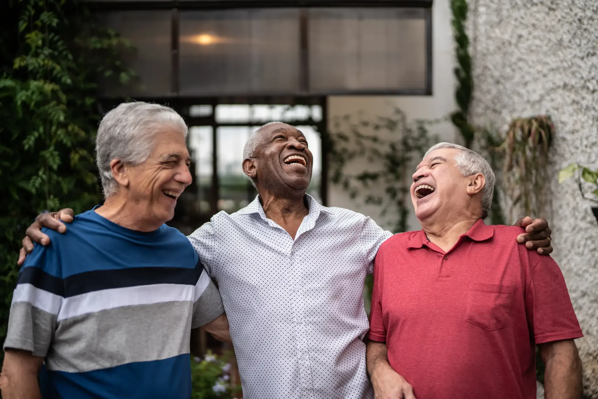Three senior men laughing together outdoors