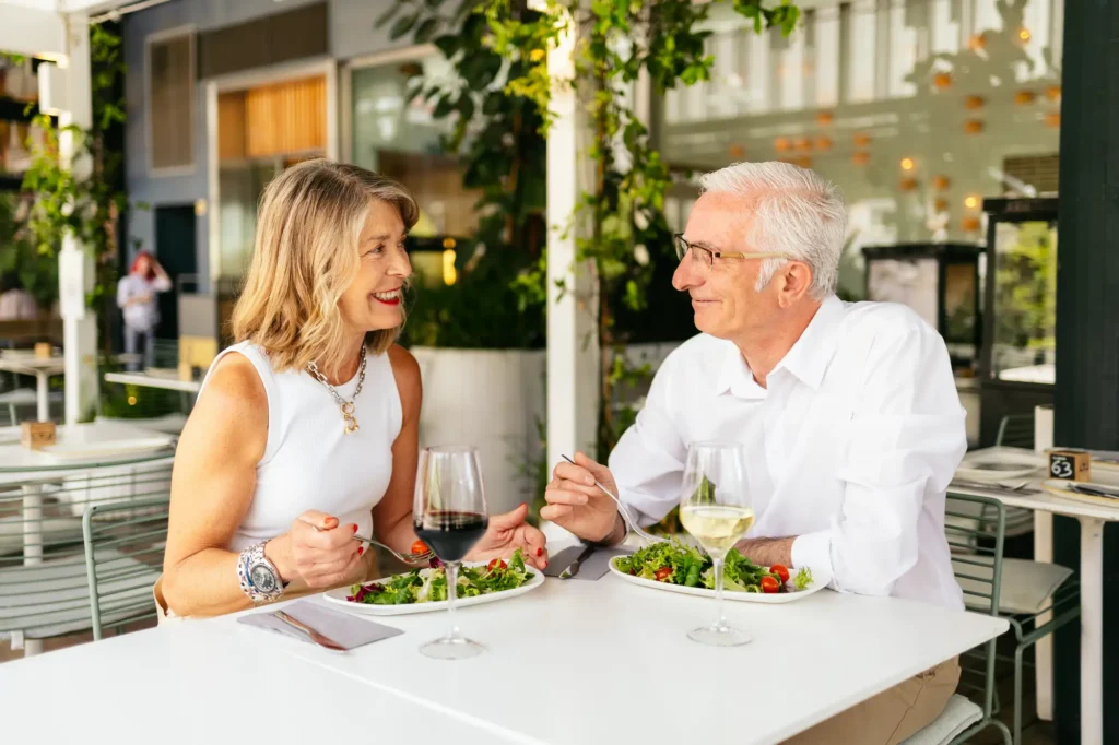 two seniors having a meal outside, enjoying the benefits of living in a Life Plan Community